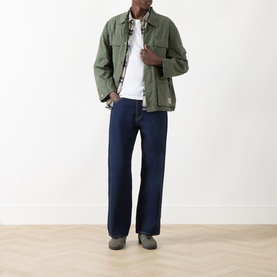 Model wearing Levi's 3049 Straight Jeans in Keep It Forever Rinse dark indigo, styled with green jacket and white tee.