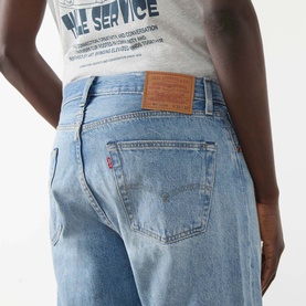 Model wearing Levi's 501&reg; Loose Jeans in In My Bronco light wash, showing rear view with logo patch and five-pocket styling, paired with graphic tee.