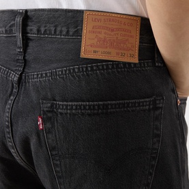 Model wearing Levi's 3049 straight jeans in Big Wheels washed black denim, close-up of back pocket with logo patch detail.