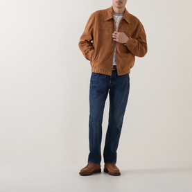 Model wearing Levi's 3049 Straight Jeans in Terra Linda dark blue denim, styled with a tan suede bomber jacket and brown shoes.