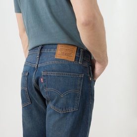 Model wearing Levi's 3049 Straight Jeans in Advice To You mid-blue wash, rear view showing leather patch tab detail, styled with teal T-shirt