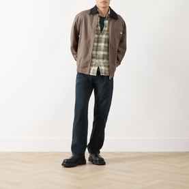 Model wearing Levi's 3049 Straight Jeans in City Boy Blues, styled with a brown zip jacket, plaid shirt and black loafers.