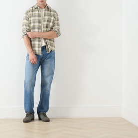 Model wearing Levi's 555 Relaxed Straight Leg Jeans in Indigo Champion, styled with a cream plaid shirt and grey trainers.