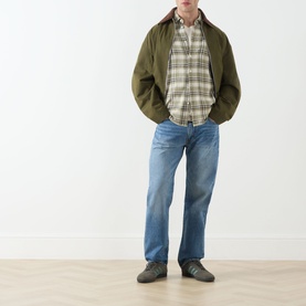 Model wearing Levi's 555 Relaxed Straight Leg Jeans in Indigo Champion, styled with olive bomber jacket and plaid shirt.