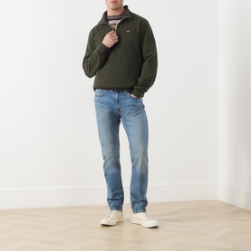 Model wearing Levis Original Housemark Logo Half-Zip Sweater in dark green, styled with light wash straight jeans and white trainers.