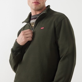 Model wearing Levis Original Housemark Logo Half-Zip Sweater in dark green with raised collar, styled with a striped top underneath.