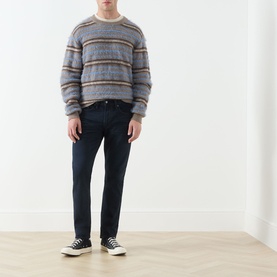 Model wearing Levi's 3049 Tapered Jeans in Why So Blue, styled with a grey striped knit and black low-top trainers.