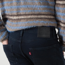 Model wearing Levi's 3049 Tapered Jeans in Why So Blue, dark indigo wash, with stripe fluffy knit top.