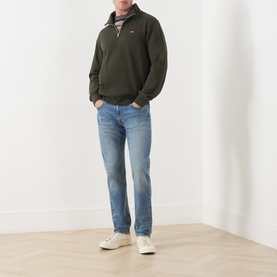 Model wearing Levi's 502&trade; Tapered Leg Jeans in Its Been A While Selvedge, mid-rise faded wash, styled with olive quarter-zip sweatshirt and white