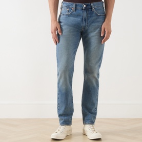 Model wearing Levi's 502&trade; Tapered Leg Jeans in Its Been A While Selvedge mid-blue faded wash, styled with white trainers.