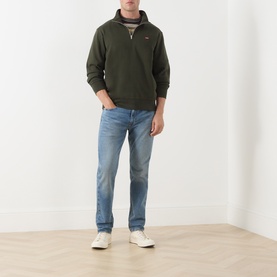 Model wearing Levi's 502&trade; Tapered Leg Jeans in Its Been A While Selvedge, mid-rise faded wash, styled with olive quarter-zip sweatshirt and white