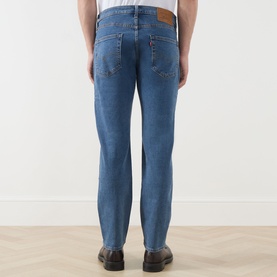 Model wearing Levi's 3049 Tapered Jeans in stonewash stretch, rear view showing five-pocket styling and leather patch detail.