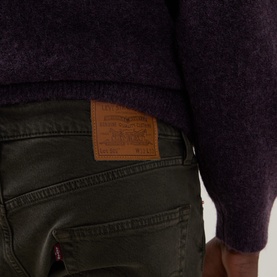 Model wearing Levi's 3049 Tapered Jeans in Redwood Bough GD, close-up of back pocket with leather logo patch, styled with purple knit jumper.