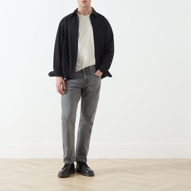 Model wearing Levis 3049 Tapered Jeans in Granite Shadow, styled with a black open jacket and cream T-shirt, black leather shoes.