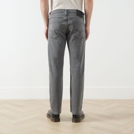 Model wearing Levi's 3049 Tapered Jeans in Granite Shadow grey, rear view, styled with brown leather boots.