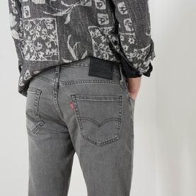 Model wearing Levi's 3049 Tapered Jeans in Granite Shadow grey, rear view showing iconic red tab and patch detail.