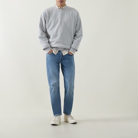 Model wearing Levis 502&trade; Tapered Leg Jeans in mid-wash blue, tapered fit, styled with grey sweatshirt and white trainers