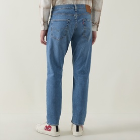 Model wearing Levi's 502&trade; Tapered Leg Jeans in mid-wash blue with tobacco stitching, styled with a check shirt and white trainers.
