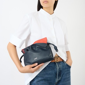 Model carrying Loewe Flamenco Mini Clutch in Multicolour Deep Navy calfskin with red interior, drawstring knot detail, styled with white shirt and