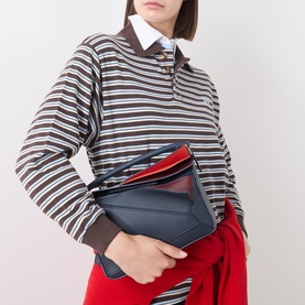 Model carrying Loewe Puzzle Edge Small Crossbody Bag in Multicolour Deep Navy with red and gold-tone hardware, styled with striped top and red