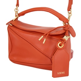 Loewe Puzzle top handle bag in deep saffron nappa lambskin with gold-tone hardware, knot detail, crossbody strap and branded tag.