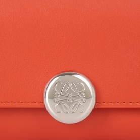 Loewe Pebble Small Vertical Wallet in Sunrise Orange smooth calfskin with silver-tone Anagram engraved snap button closure detail.