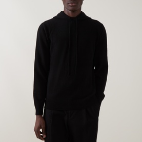 Model wearing Seven Jeans Hooded Cashmere Sweater in Coal, featuring drawstring hood and long sleeves, styled with black trousers.