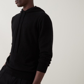 Model wearing Seven Jeans Hooded Cashmere Sweater in Coal, featuring drawstring hood and long sleeves, styled with black trousers.