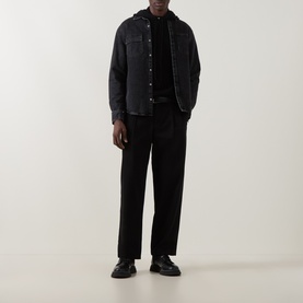 Model wearing Seven Jeans Hooded Cashmere Sweater in Coal, styled with black denim overshirt, tailored trousers and leather shoes.
