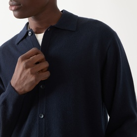 Model wearing Seven Jeans Cashmere Knitted Polo Shirt in Midnight, featuring polo collar and button fastenings, styled over a white crew-neck tee.