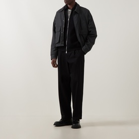 Model wearing Seven Jeans Black Polo Collar Zip Sweater with black trousers, striped T-shirt underneath, and black loafers.