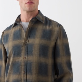 Model wearing Seven Jeans Reg Shirt in Cottage, olive and blue ombre plaid check, long-sleeved with button front, over grey crew-neck tee