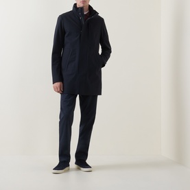 Model wearing Boggi Milano Longline Car Coat in navy blue with stand collar and snap button placket, styled with navy trousers and cream trainers.