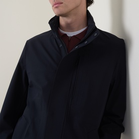 Model wearing Boggi Milano Longline Car Coat in navy blue, featuring stand collar and concealed zip fastening, styled with burgundy layered top.