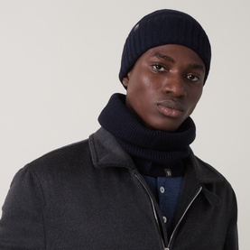 Model with Boggi Milano Merino Logo Badge Beanie Hat in navy blue, ribbed knit with turn-up brim, styled with matching navy snood and dark coat