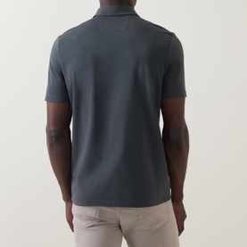 Model wearing Boggi Milano dark green cotton polo shirt, rear view, styled with light beige trousers