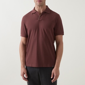 Model wearing Boggi Milano Brick Red polo shirt, short sleeves and open collar, styled with dark trousers.