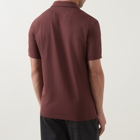 Model wearing Boggi Milano brick red polo shirt, rear view, short sleeves, smooth piqu&eacute; fabric, styled with dark trousers.