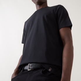 Model wearing Boggi Milano Supima Solid T-Shirt in black, round neck, short sleeves, styled with a black belt and trousers.