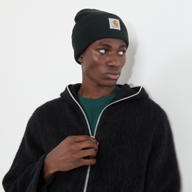 Model with Carhartt Watch Logo Beanie Hat in Raven, featuring turned-up brim and logo badge, styled with black zip-up fleece jacket