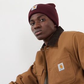 Model with Carhartt Watch Logo Beanie Hat in Amarone burgundy, knit with turned-up brim and logo badge, styled with tan workwear jacket