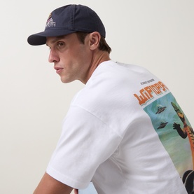 Model with Carhartt Wiptopia 2 Cap in Shady Purple, flat peak five-panel design, worn with white graphic print T-shirt