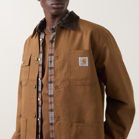 Model wearing Carhartt Hamilton Brown casual jacket with corduroy collar and chest pockets, styled over brown plaid shirt