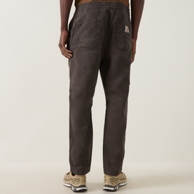 Model wearing Carhartt Casual Trouser in Shungite brown, rear view, relaxed fit with elasticated waist, styled with tan trainers.