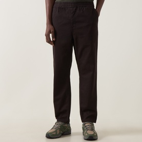 Model wearing Carhartt Casual Trouser in Tobacco brown cotton, styled with green and grey chunky trainers.
