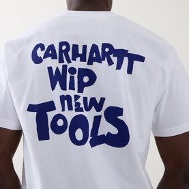 Model wearing Carhartt New Tools Logo Back Graphic T-Shirt in white, showing bold blue "Carhartt WIP New Tools" back graphic print.