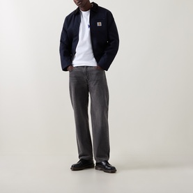 Model wearing Carhartt New Tools Logo Back Graphic T-Shirt in white, styled with navy jacket and grey jeans.