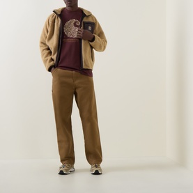 Model wearing Carhartt Entrance Logo Graphic T-Shirt in Amarone, styled with tan fleece jacket, brown trousers and grey trainers.