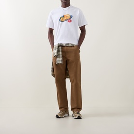 Model wearing Carhartt white crew neck T-shirt with planet graphic, styled with tan trousers and plaid shirt tied at waist.