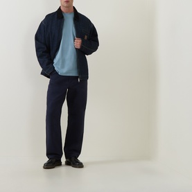 Model wearing Carhartt Crew Neck T in Citadel blue, styled with navy zip jacket and navy drawstring trousers.
